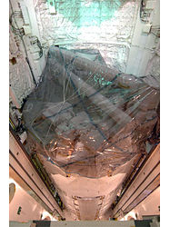 （ディスカバリー号の貨物室に搭載される日本実験棟「きぼう」の船内実験室とロボットアームの画像）