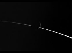 （土星の明るい大気がつくる弧の上に浮かぶエンケラドスの画像）