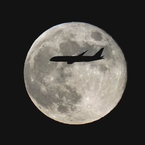 満月を通過する飛行機