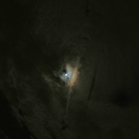 飛行機が切り裂いた雲を照らす満月