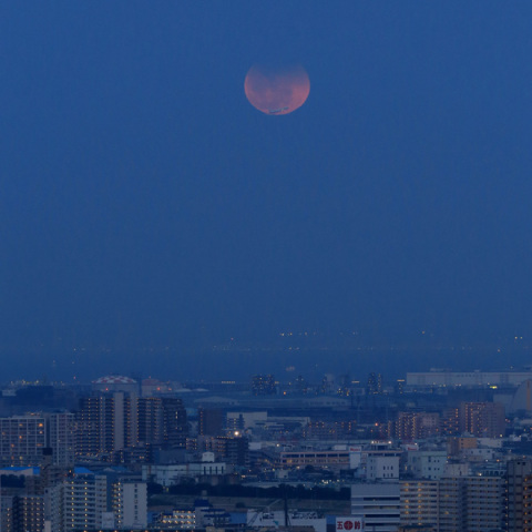 月食中の月を横切る飛行機