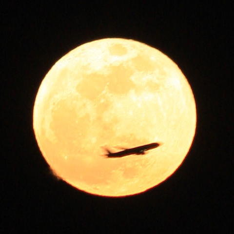 スーパームーンを横切るジェット機