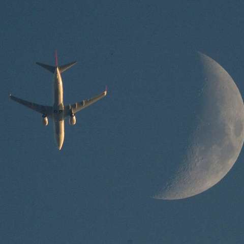 夕日に照らされた飛行機と月