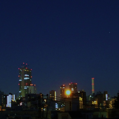 ビルの谷間に沈む満月