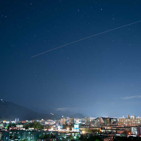 街明かりと国際宇宙ステーションの光跡
