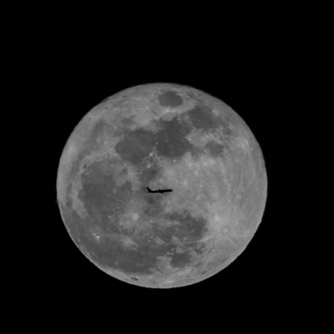 スーパームーンを横切る飛行機